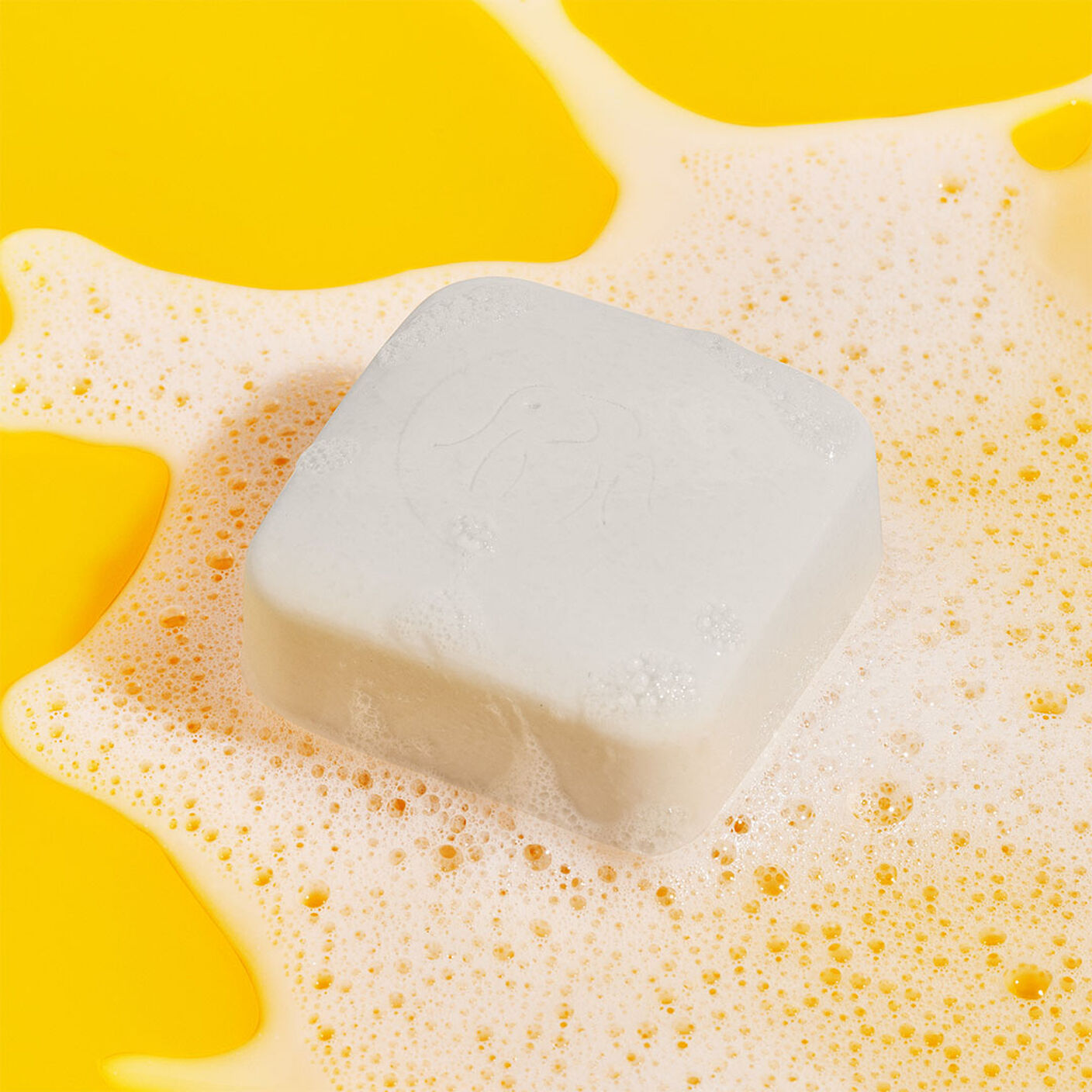 Pekee Bar on a a yellow table on top of soapy water. 